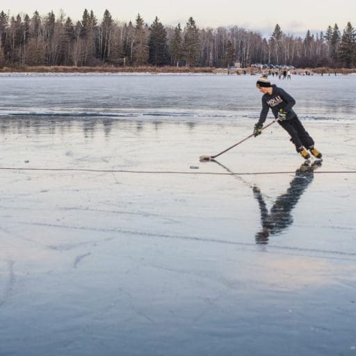 Young person skating on Clear Lake with a hokey stick.