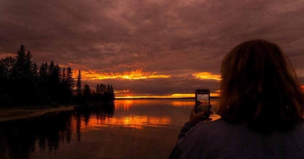 Someone taking a picture of the Clear Lake sunset on their phone.